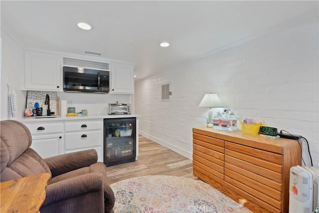 interior space with light wood-type flooring, brick wall, and beverage cooler