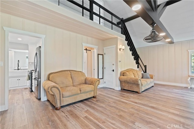 living room featuring a high ceiling, sink, and light hardwood / wood-style flooring