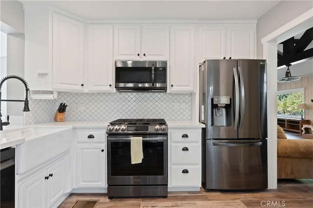 kitchen with white cabinets, backsplash, appliances with stainless steel finishes, and sink