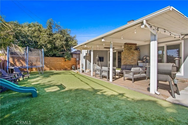 rear view of property with a playground, outdoor lounge area, a yard, and a trampoline