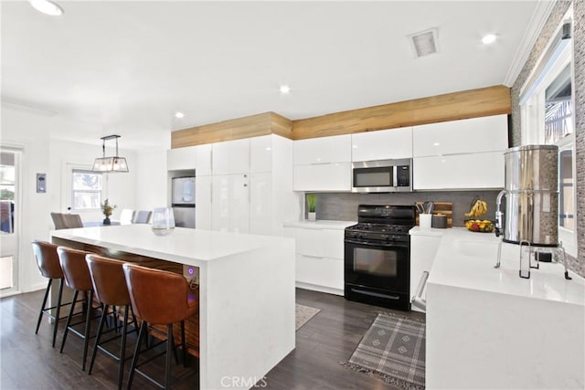 kitchen featuring pendant lighting, appliances with stainless steel finishes, dark hardwood / wood-style floors, white cabinets, and decorative backsplash