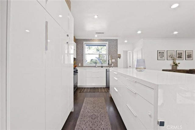 kitchen with dark hardwood / wood-style floors, tasteful backsplash, white cabinets, ornamental molding, and range