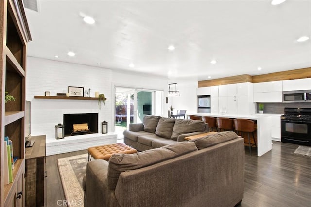 living room with a brick fireplace and dark hardwood / wood-style floors