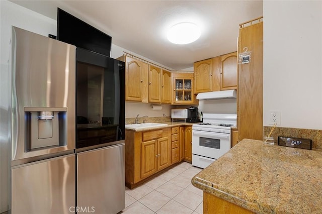 kitchen with stainless steel refrigerator with ice dispenser, light stone counters, sink, white stove, and light tile patterned flooring