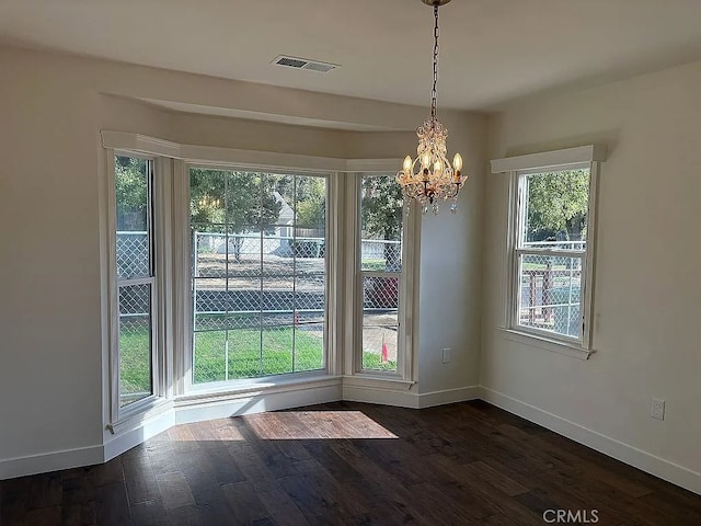 unfurnished dining area featuring plenty of natural light, dark hardwood / wood-style floors, and a notable chandelier