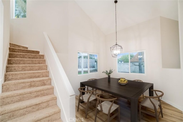 dining area featuring a chandelier, hardwood / wood-style flooring, and high vaulted ceiling