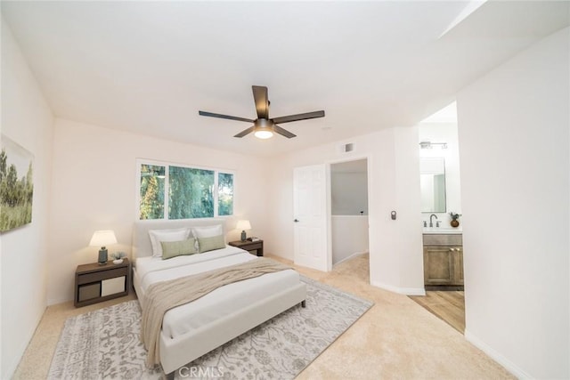 bedroom with ceiling fan, sink, light carpet, and connected bathroom