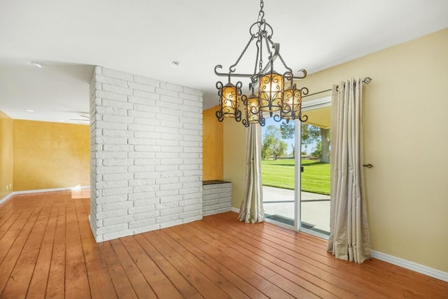 unfurnished dining area featuring a notable chandelier and light hardwood / wood-style floors