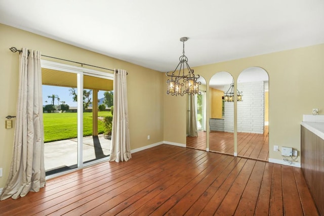 unfurnished dining area featuring an inviting chandelier and hardwood / wood-style floors