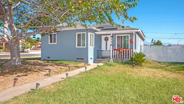 bungalow-style house featuring a front yard and solar panels