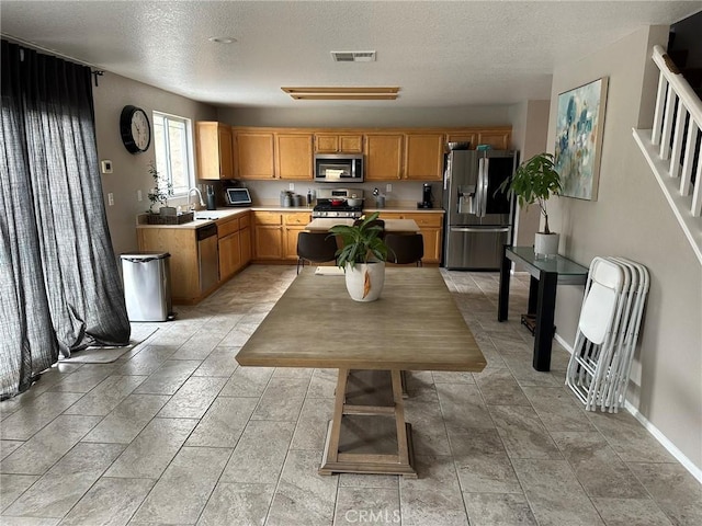 kitchen with sink, a textured ceiling, and appliances with stainless steel finishes