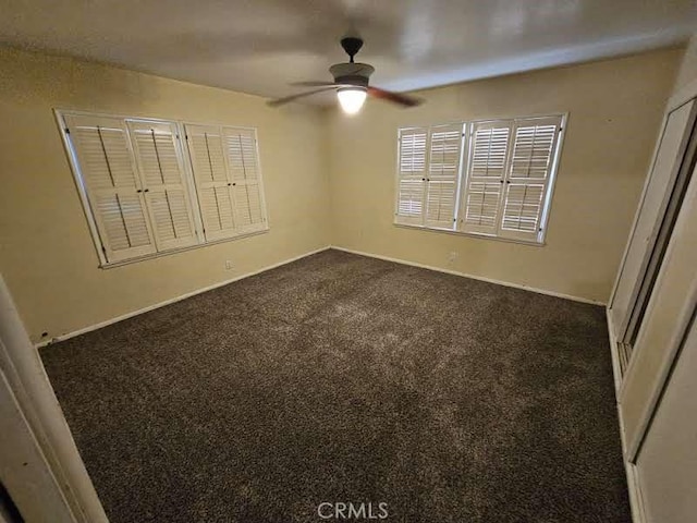 spare room featuring ceiling fan and dark carpet