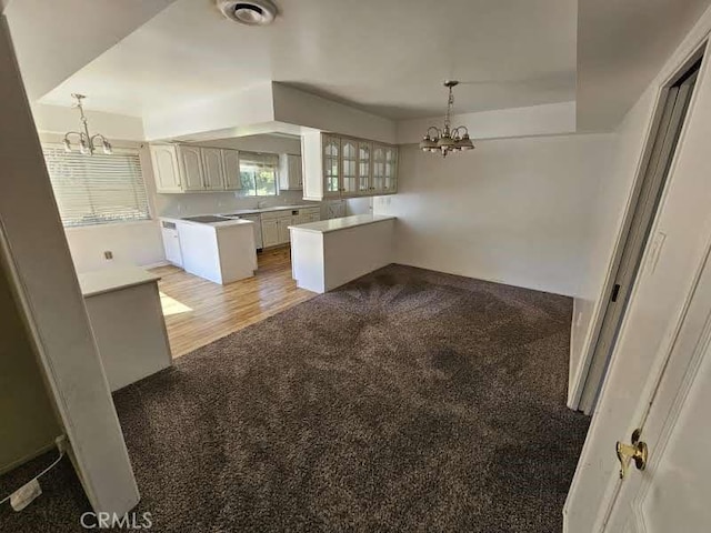 kitchen featuring white cabinets, pendant lighting, light hardwood / wood-style flooring, and a chandelier