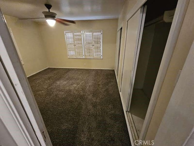 unfurnished bedroom with ceiling fan and dark carpet