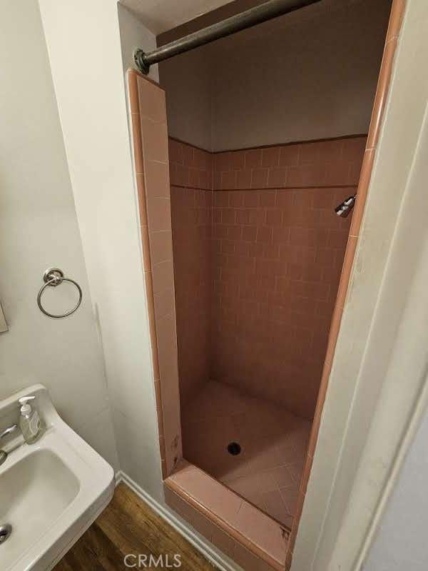 bathroom with a tile shower, hardwood / wood-style floors, and sink