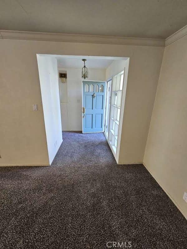 unfurnished room featuring crown molding, carpet, and an inviting chandelier