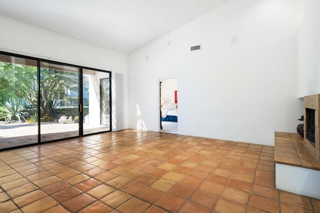 interior space featuring a tiled fireplace, high vaulted ceiling, and light tile patterned flooring