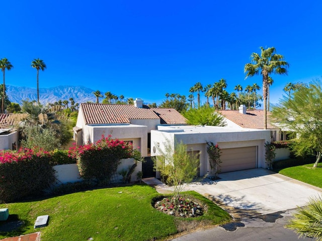 mediterranean / spanish home featuring a mountain view, a front lawn, and a garage