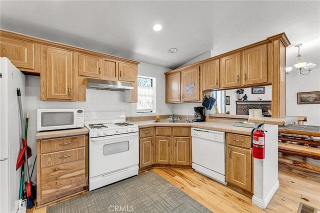 kitchen with light wood-type flooring, white appliances, sink, a chandelier, and lofted ceiling