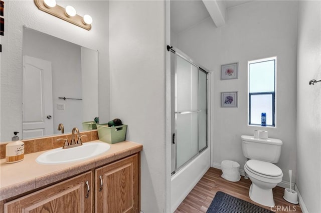 full bathroom featuring beamed ceiling, combined bath / shower with glass door, toilet, vanity, and hardwood / wood-style flooring