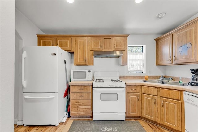 kitchen featuring tile countertops, sink, white appliances, and light hardwood / wood-style flooring