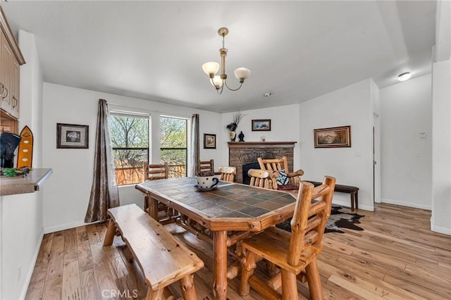 dining area with a notable chandelier, light hardwood / wood-style floors, and a fireplace