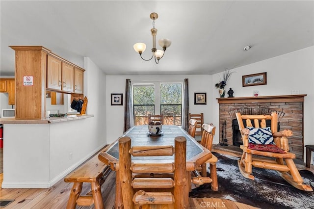 dining room featuring light hardwood / wood-style floors, a fireplace, and a chandelier