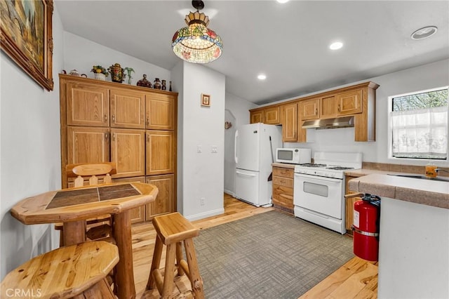 kitchen featuring vaulted ceiling, sink, light hardwood / wood-style floors, and white appliances