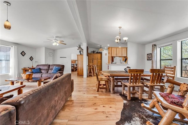 living room with vaulted ceiling with beams, light hardwood / wood-style flooring, and ceiling fan with notable chandelier