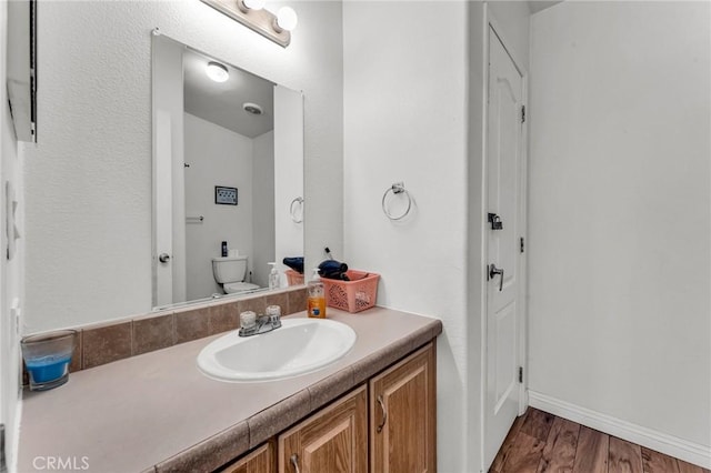 bathroom featuring wood-type flooring, vanity, and toilet