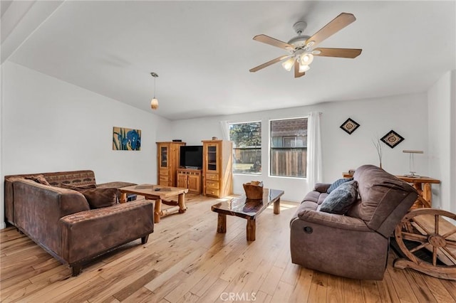 living room with ceiling fan, vaulted ceiling, and light hardwood / wood-style flooring