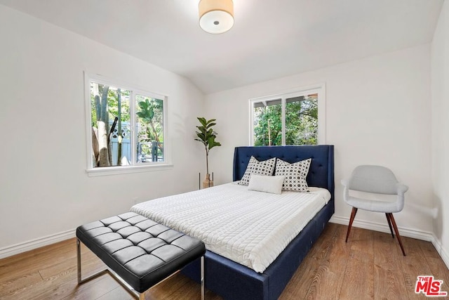 bedroom with multiple windows, lofted ceiling, and hardwood / wood-style flooring