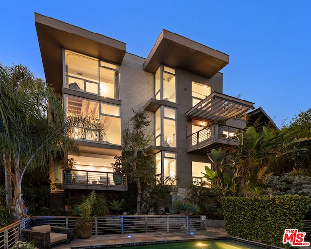 back house at dusk with a balcony