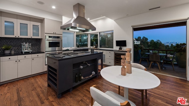 kitchen with dark wood-type flooring, tasteful backsplash, island range hood, white cabinetry, and stainless steel appliances