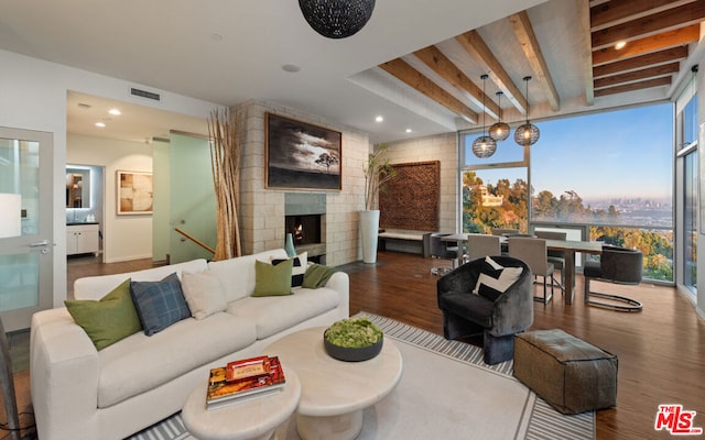 living room featuring hardwood / wood-style floors, beam ceiling, and a large fireplace