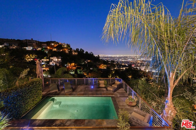 pool at dusk featuring a hot tub