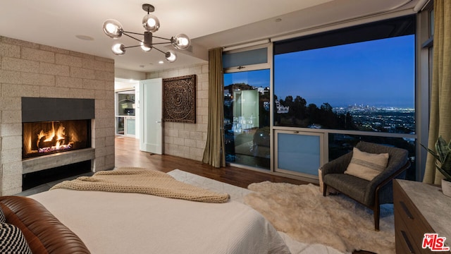 bedroom with dark hardwood / wood-style flooring, a large fireplace, and an inviting chandelier