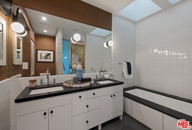 bathroom featuring a washtub, vanity, a skylight, and tile walls