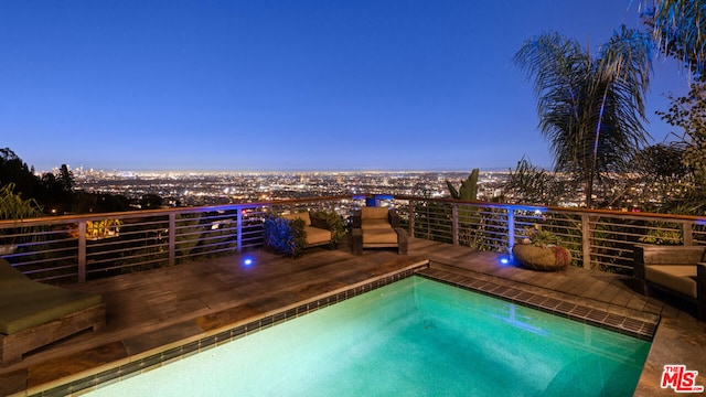 pool at dusk with a hot tub and a deck