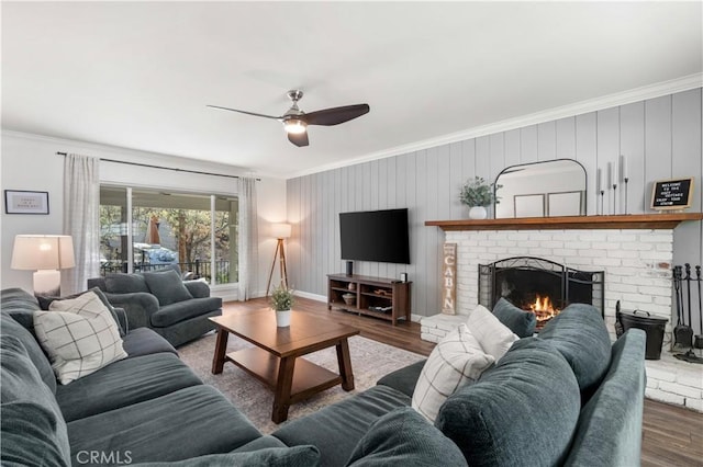 living room with hardwood / wood-style floors, a brick fireplace, ceiling fan, and ornamental molding