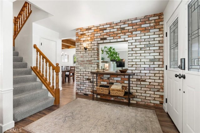 entrance foyer with a chandelier, dark hardwood / wood-style floors, and brick wall