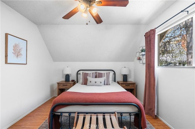 bedroom featuring ceiling fan, light wood-type flooring, and vaulted ceiling