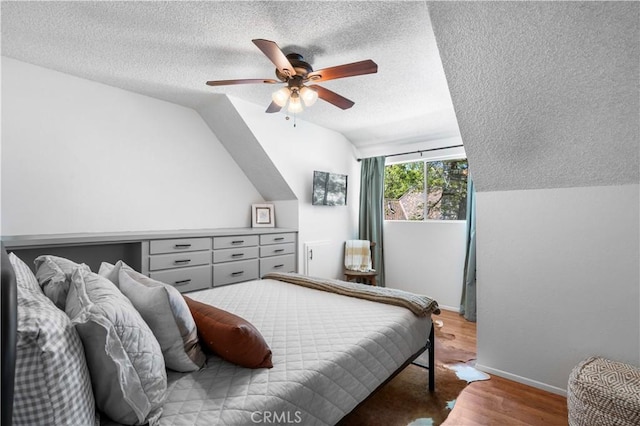 bedroom with a textured ceiling, hardwood / wood-style flooring, ceiling fan, and lofted ceiling