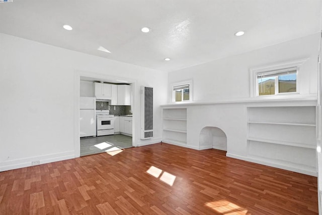 unfurnished living room with built in features and wood-type flooring