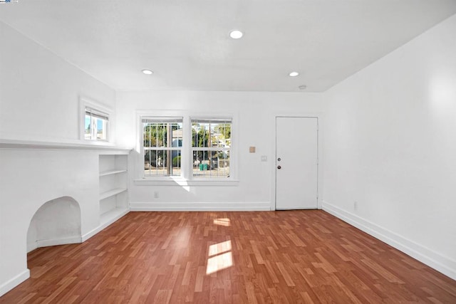 unfurnished living room featuring light hardwood / wood-style floors and built in shelves