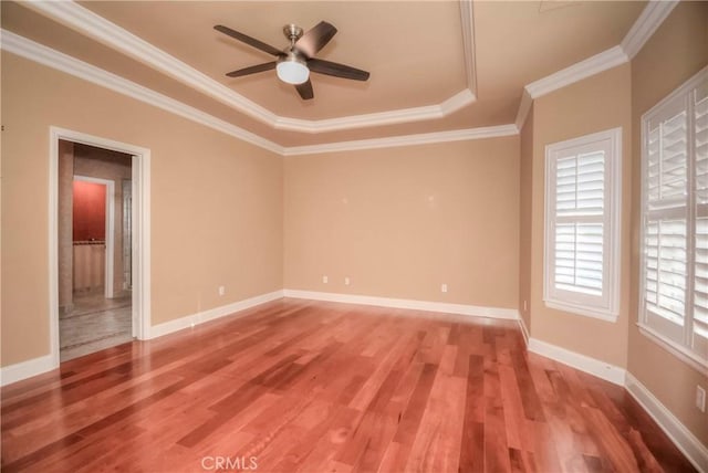 empty room with hardwood / wood-style floors, a tray ceiling, ceiling fan, and crown molding