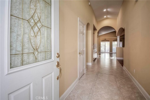 hallway featuring light tile patterned flooring and vaulted ceiling