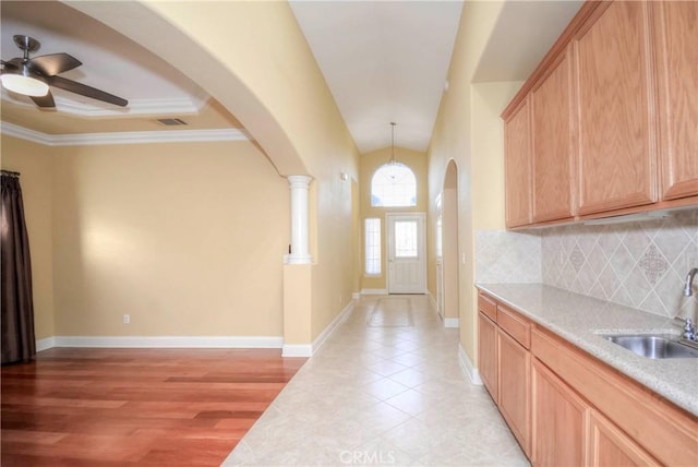 interior space featuring sink, hanging light fixtures, backsplash, light hardwood / wood-style floors, and ornamental molding