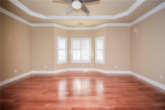 spare room featuring wood-type flooring, a raised ceiling, ceiling fan, and crown molding