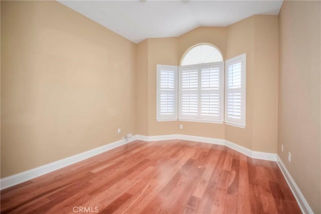 unfurnished room with hardwood / wood-style floors and vaulted ceiling